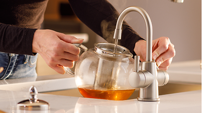 Kitchen instant hot water tap filling a glass teapot