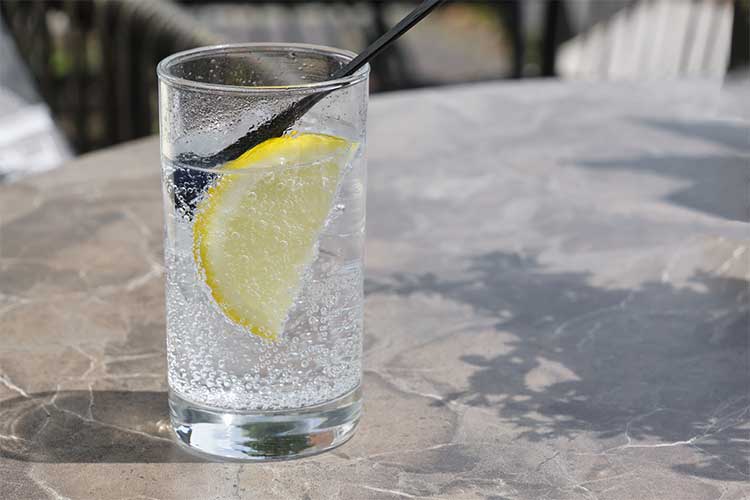 Clear water pouring into a glass with a snowy mountain backdrop